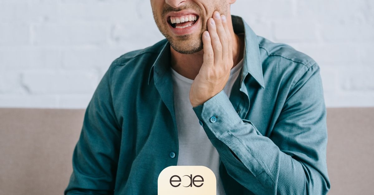 : Man holding his cheek while experiencing sharp tooth discomfort when biting down, illustrating localized pain that may be associated with a cavity or deeper tooth decay