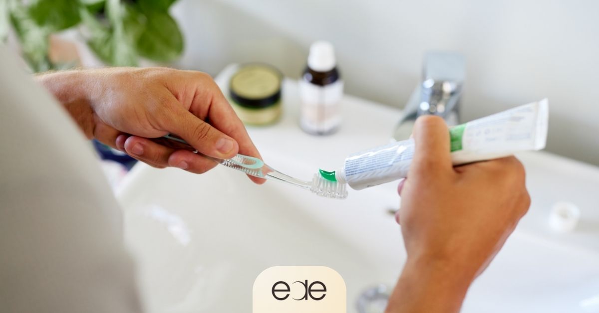 Person applying fluoride toothpaste to a toothbrush, illustrating daily oral hygiene habits that help protect enamel and reduce cavity risk after consuming sugary foods and drinks