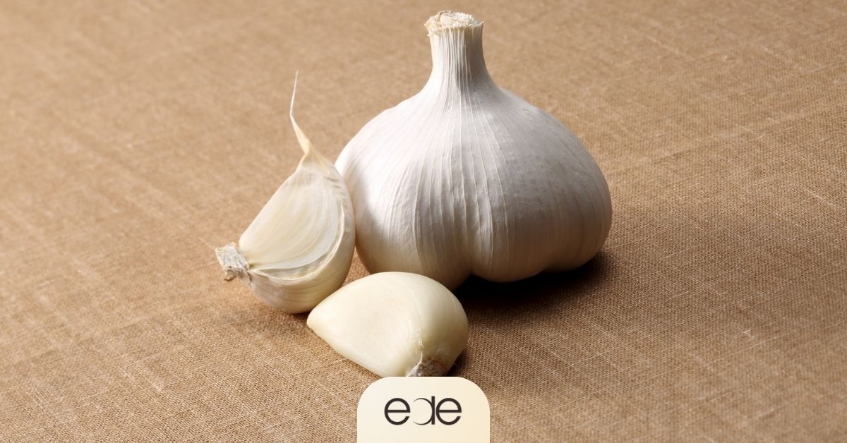 Garlic bulb with peeled and unpeeled cloves on a brown surface.