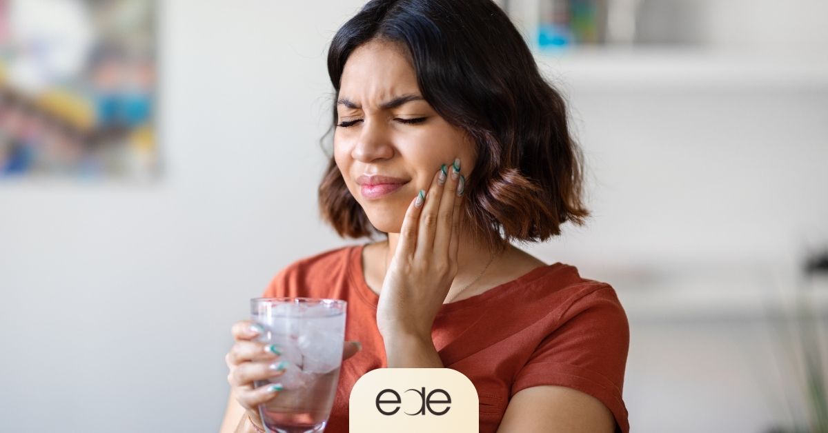 Woman experiencing sharp tooth sensitivity while drinking cold water with ice