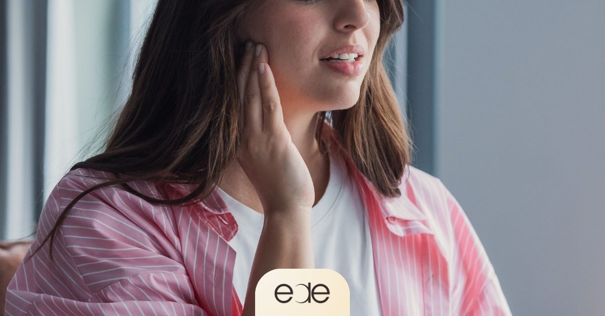 Person touching the jaw area while experiencing TMJ-related discomfort and jaw pain associated with chronic stress